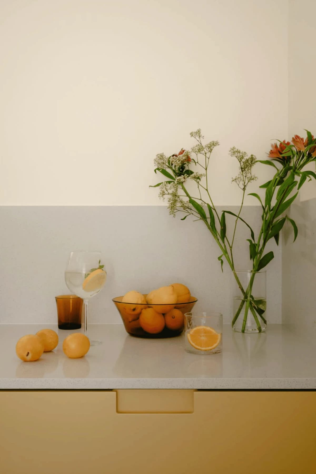 Flores, cítricos y bebidas sobre la encimera de una cocina amarilla